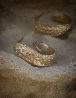 Kreolernes tekstur får mig til at tænke på et korallrevs porøse overflade, eroderet af århundreders bølgeslag. De tætsiddende knopper og uregelmæssige fordybninger skaber et relief, der genskinner som dråber på en grusvej, regnen netop har forladt. Smykket gengiver den uforfalskede skønhed, der findes, når materialer får lov til at tale deres eget sprog. 🕊️
Find kreolerne i butikken og på webshoppen under navnet "Angitia" ✨